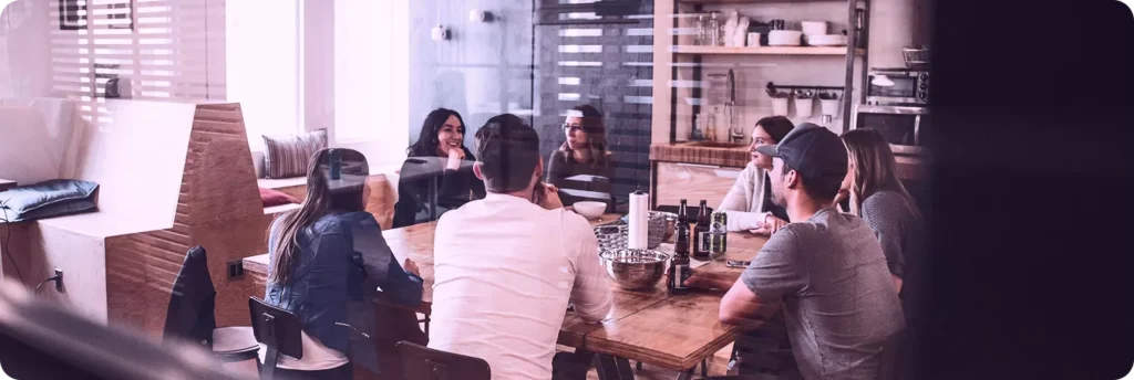 A group of people sitting around a wooden table in a bright, modern office space.